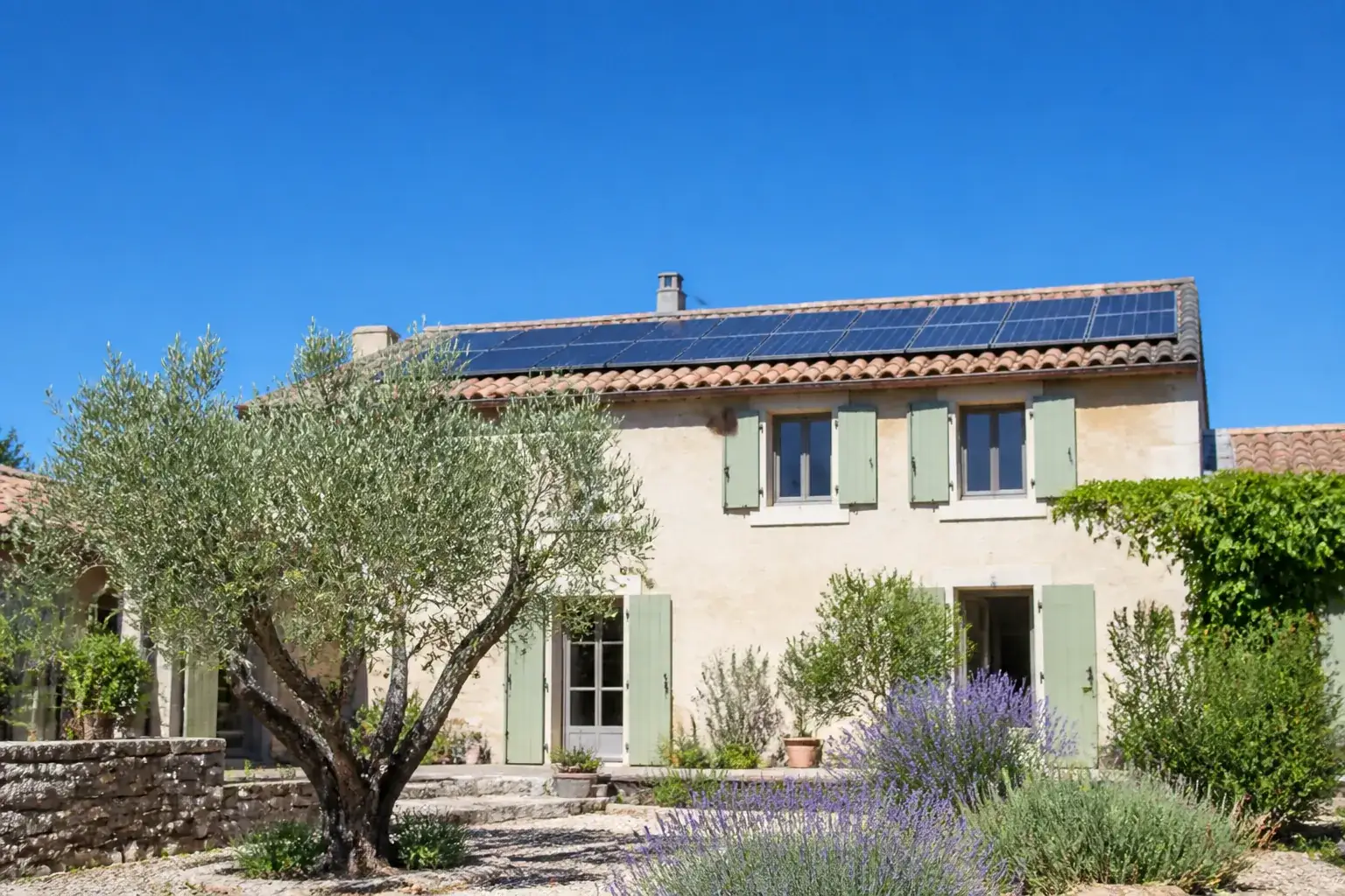 Façade sud d’une maison provençale avec toiture équipée de panneaux solaires